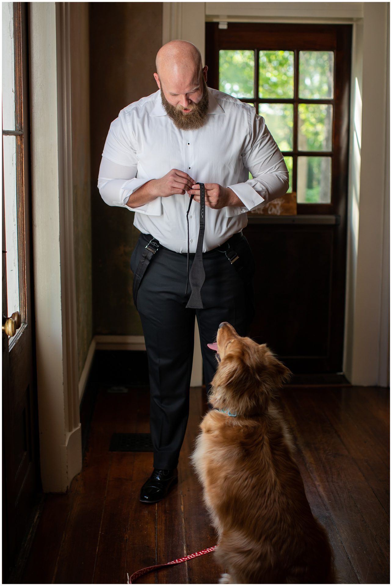 Groom getting ready for his wedding with his dog watching him at Riverwood Mansion